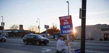 ناخب يحمل إحدى لافتات الدعاية في الانتخابات الأمريكية