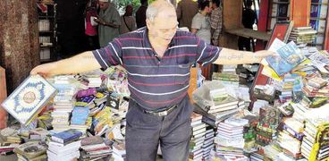 صاحب أحد أكشاك الجرائد يحمل الكتب على الرصيف