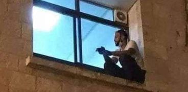 صورة الشاب الفلسطيني جهاد أثناء تواجده على نافذة غرفة والدته بالعزل