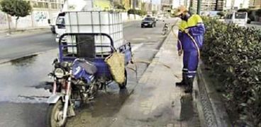 عامل يقوم بتنظيف شوارع الإسكندرية بالاعتماد على «التروسيكل»