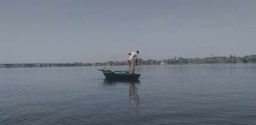 أحد الصيادين في مياه النيل يرمي الشباك