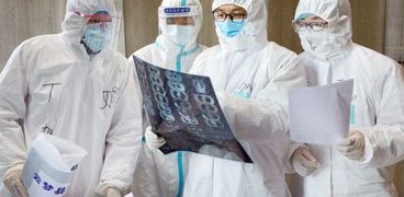 أطباء صينيون يطالعون صورة الأشعة الخاصة بأحد مصابي كورونا - أرشيفية