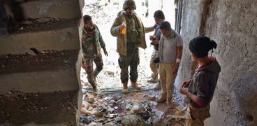 قوات من الجيش السورى حول جثة إرهابى بعد قصف مدينة الحمدانية
