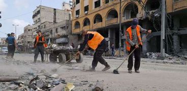 عمال يزيلون أنقاض المباني التي دمرها القصف من شوارع غزة