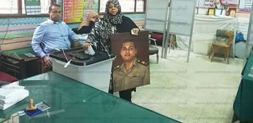 شقيقة "صائد التكفيريين" تحمل صورته خلال تصويتها ببني سويف