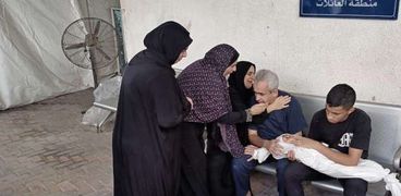 فلسطيني يحمل ابنه الطفل الشهيد