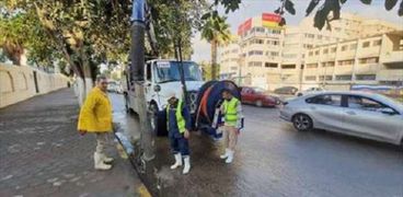 عاملون بشركة مياه الصرف بالجيزة أثناء شفط المياه من الشوارع أمس