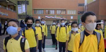 طلاب المدارس يلتزمون بارتداء الكمامات الطبية للوقاية من كورونا في الطابور الصباحي