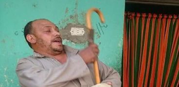 كامل عبدالنبى المسحراتى يمسك بالعصا التى يستخدمها فى إيقاظ المواطنين