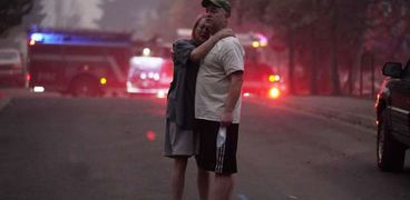 زوجان يحتضنان بعضهما بعد أن دمرت حرائق الغابات منزلهما