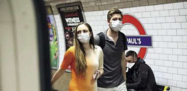 بريطانيان يرتديان "الكمامة" كإجراء احترازي ضد "كورونا"