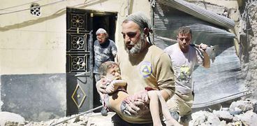 مواطن سورى يحمل جثمان طفل تم انتشاله من تحت الأنقاض «أ.ف.ب»