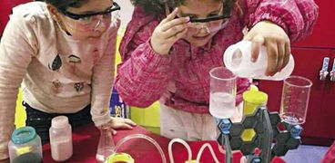 طفلتان تستمتعان بإجراء إحدى التجارب العلمية