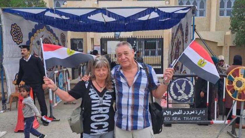 صورة سائح ألماني وزوجته يحملان أعلام مصر أمام لجان الانتخابات الرئاسية بمرسى علم – المحافظات